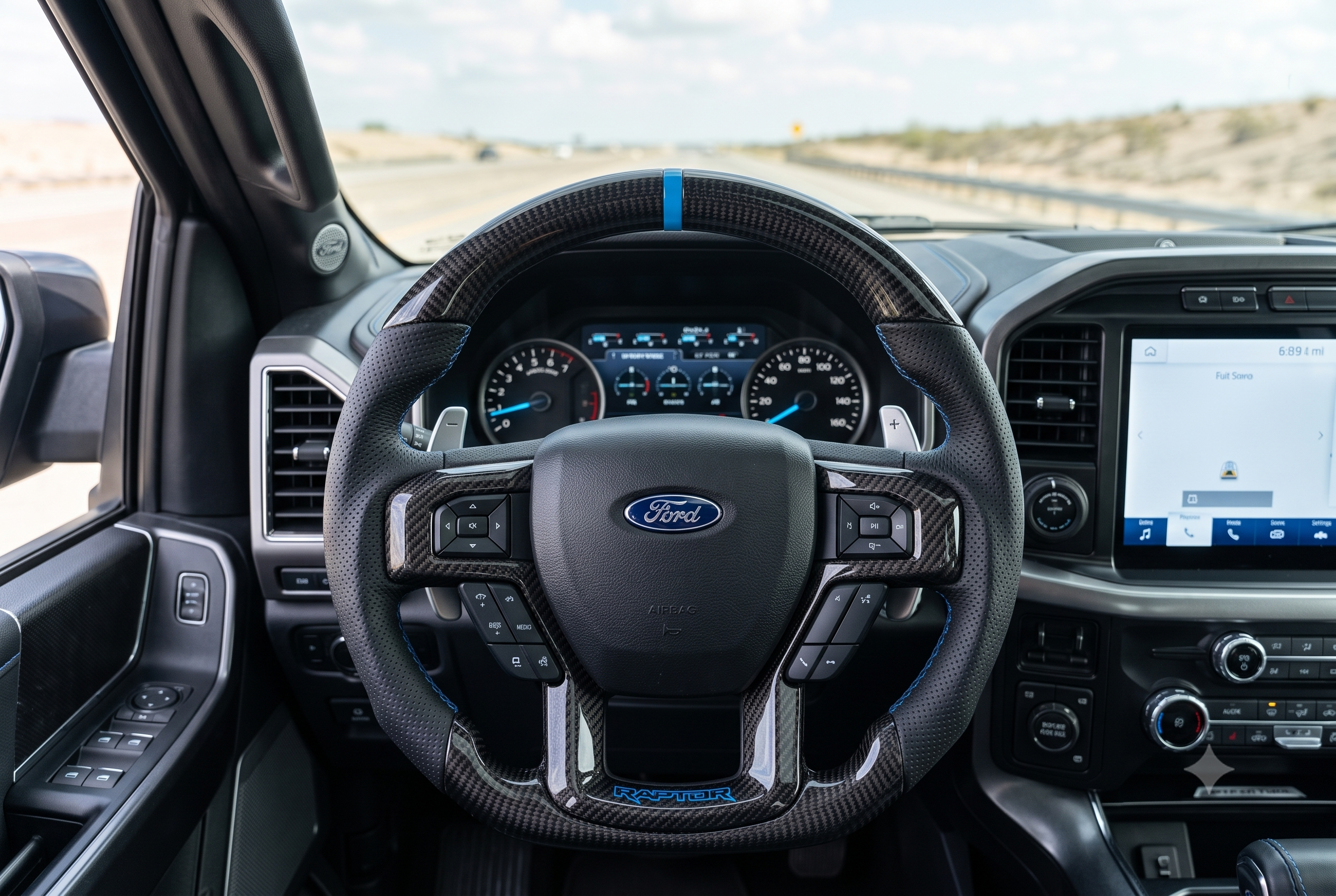 Custom Ford F-150 Raptor carbon fiber steering wheel with blue stripe installed in driver cockpit.