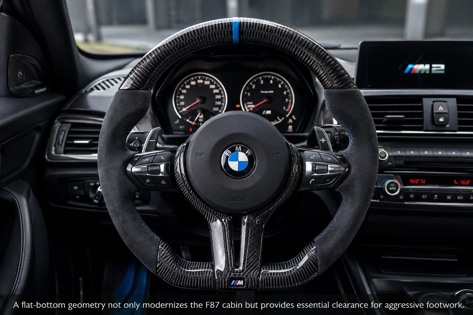 Custom BMW F87 M2 steering wheel in gloss carbon fiber and Alcantara with a blue 12 o'clock stripe.